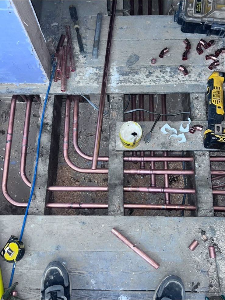 Copper heating pipework run beneath lifted floorboards