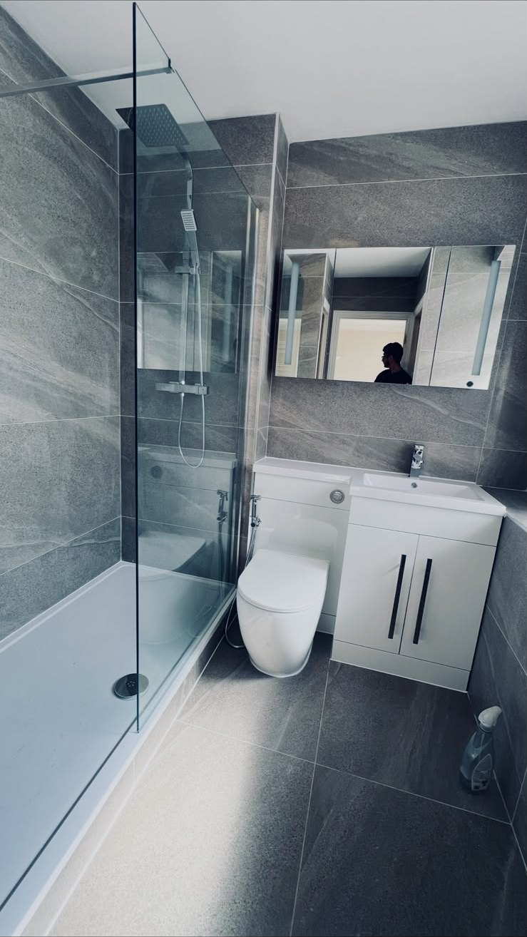 Completed grey tiled bathroom with walk-in shower and wall-hung WC